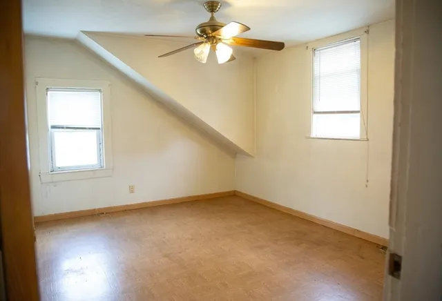 an empty room with windows and fan