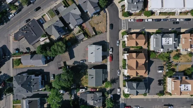 an aerial view of a house with backyard space and a car park