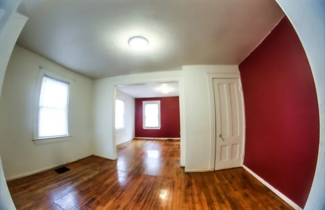an empty room with wooden floor and windows