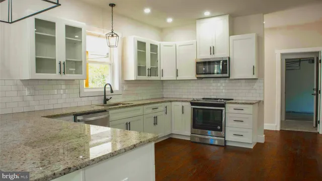 a kitchen with stainless steel appliances granite countertop a stove a sink and a microwave