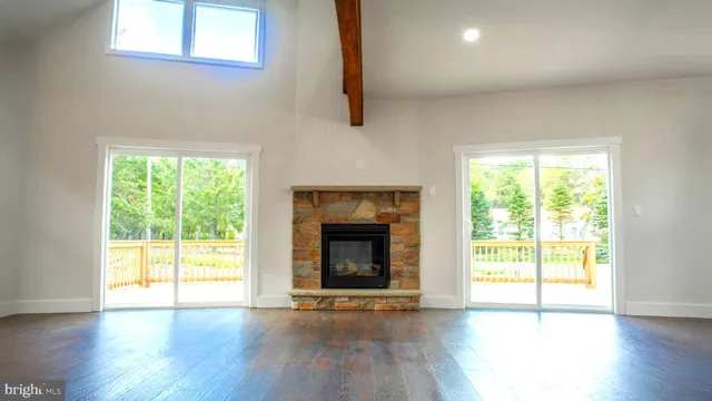 an empty room with wooden floor fireplace and windows