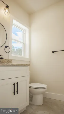a bathroom with a granite countertop toilet sink and mirror