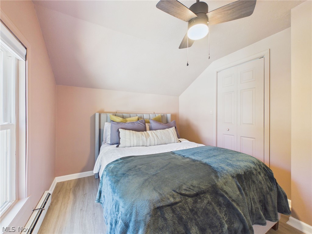 3490 County Line Road Madison, OH 44057 - Photo 32 of 42 Sloped ceiling room featuring wood-finish flooring, a window with white trim, and a ceiling fan with integrated lighting