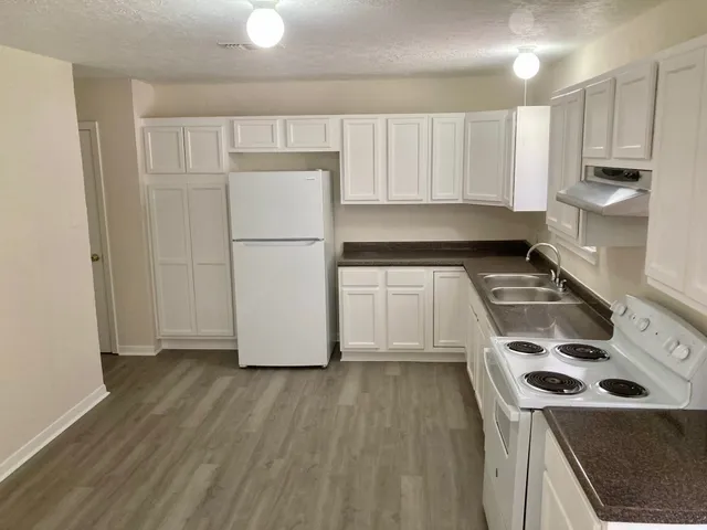 a kitchen with a refrigerator a stove top oven and white cabinets