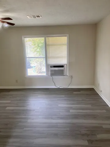 a view of empty room with wooden floor and fan