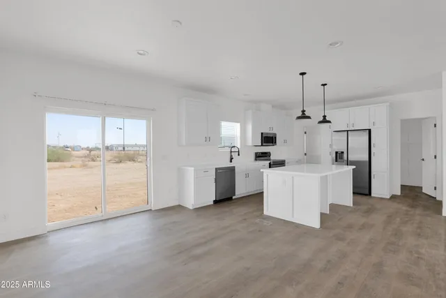 a view of a kitchen with refrigerator and white cabinets
