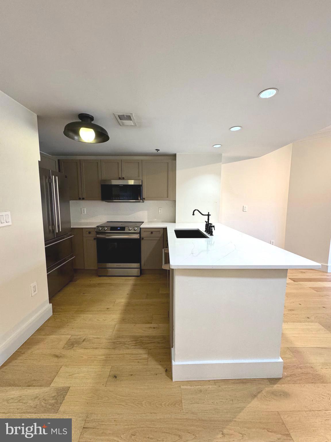 777 7th Street Northwest, Unit 322 Washington, DC 20001 - Photo 6 of 23 a kitchen with stainless steel appliances a stove a microwave and white cabinets