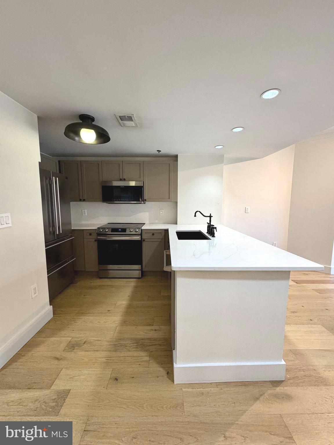 777 7th Street Northwest, Unit 322 Washington, DC 20001 - Photo 7 of 23 a kitchen with stainless steel appliances a stove a microwave and a sink