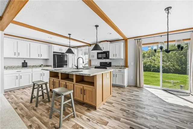 a kitchen with kitchen island granite countertop a stove a sink dishwasher a refrigerator with cabinets and wooden floor