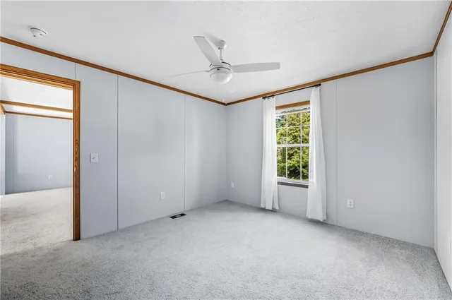 an empty room with windows and ceiling fan