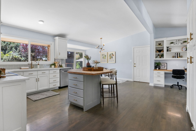576 East 3950 North Provo, UT 84604 - Photo 17 of 47 Open-concept kitchen and living area featuring wood-finish flooring, white cabinetry, an island with seating, a built-in desk area, and large windows