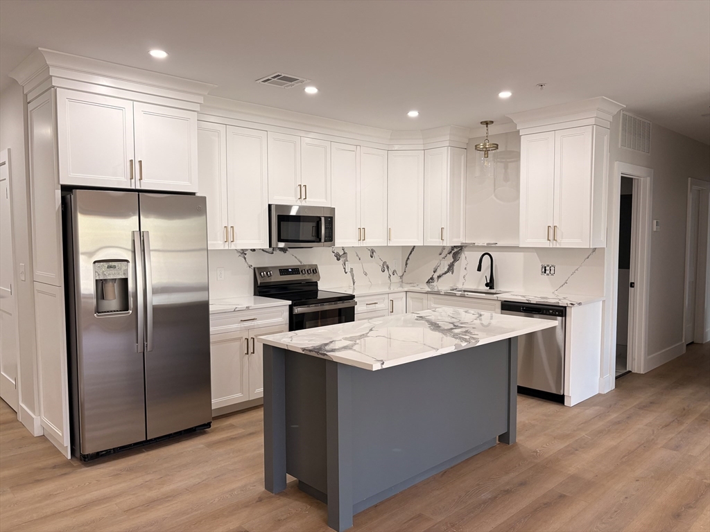 a kitchen with kitchen island a sink stainless steel appliances and refrigerator
