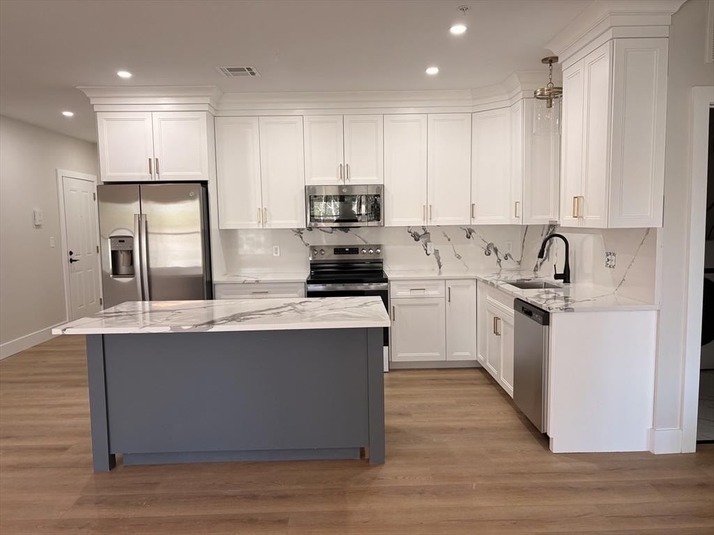441 Washington Street, Unit 305 Dedham, MA 02026 - Photo 2 of 20 a kitchen with kitchen island granite countertop a sink cabinets and stainless steel appliances