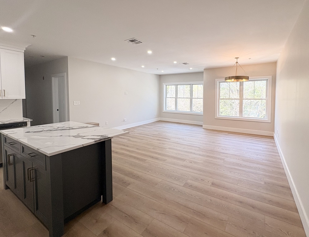 441 Washington Street, Unit 305 Dedham, MA 02026 - Photo 3 of 20 an empty room with wooden floor and windows