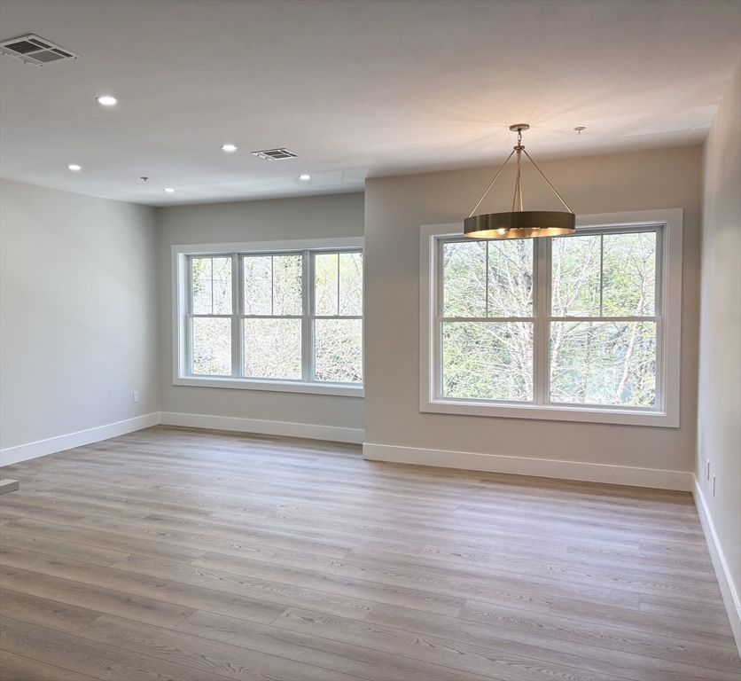441 Washington Street, Unit 305 Dedham, MA 02026 - Photo 4 of 20 an empty room with wooden floors and windows