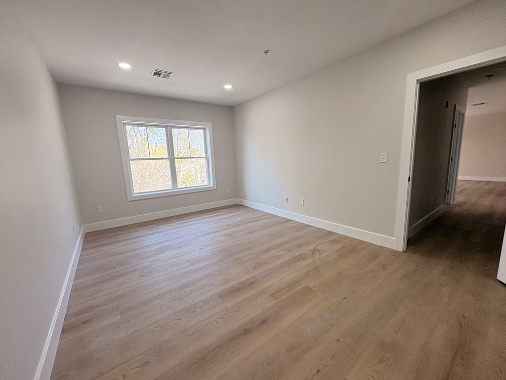 441 Washington Street, Unit 305 Dedham, MA 02026 - Photo 10 of 20 an empty room with wooden floor and windows
