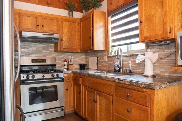 a kitchen with stainless steel appliances granite countertop a stove a sink and a microwave