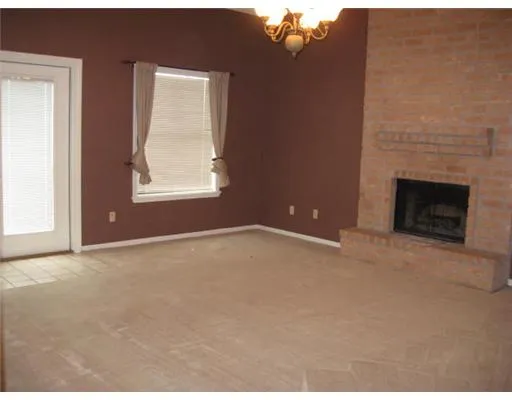 an empty room with windows and fireplace