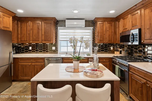 a kitchen with stainless steel appliances kitchen island granite countertop a stove a sink a microwave dining table and chairs