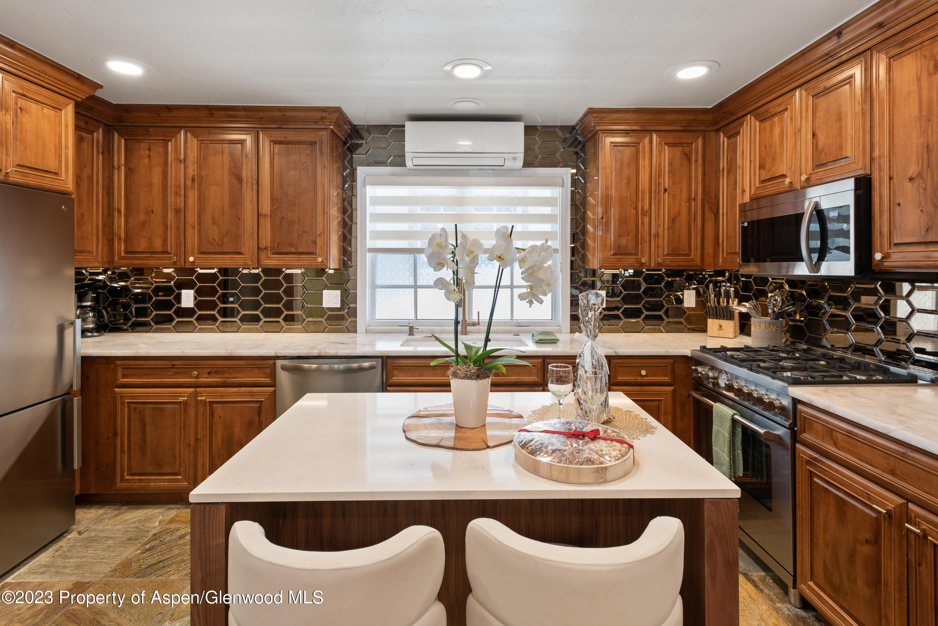 711 South Galena Street, Unit 20D Aspen, CO 81611 - Photo 9 of 26 a kitchen with stainless steel appliances kitchen island granite countertop a stove a sink a microwave dining table and chairs