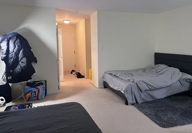 a bedroom with a bed and dresser with wooden floor