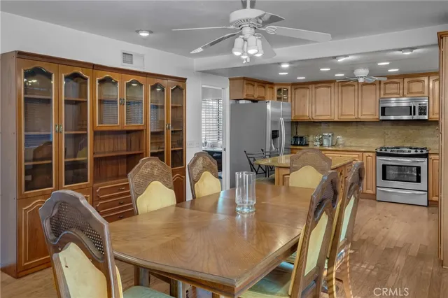 a kitchen with stainless steel appliances granite countertop a stove top oven a sink a dining table and chairs with wooden floor