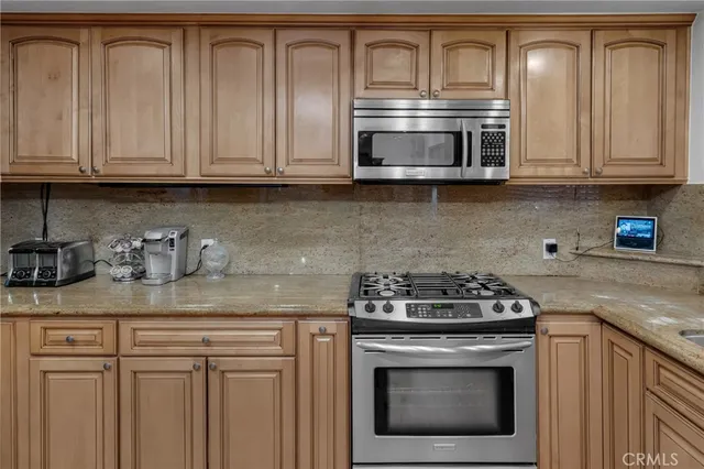 a kitchen with granite countertop white cabinets and stainless steel appliances