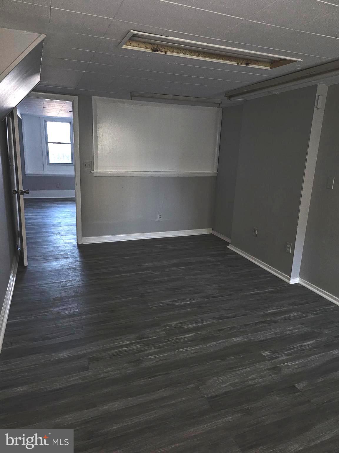 3607 Belair Road, Unit BSMT Baltimore, MD 21213 - Photo 11 of 14 a view of an empty room with wooden floor and a window