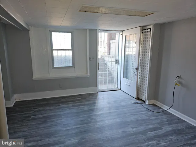 an empty room with wooden floor closet and windows