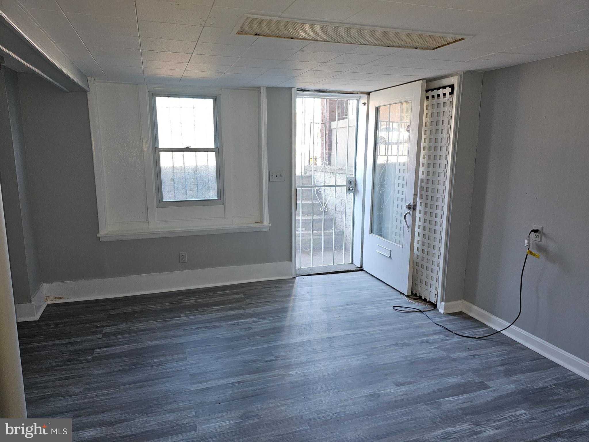 3607 Belair Road, Unit BSMT Baltimore, MD 21213 - Photo 5 of 14 an empty room with wooden floor and windows