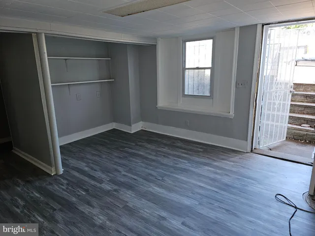 a view of an empty room with wooden floor and closet