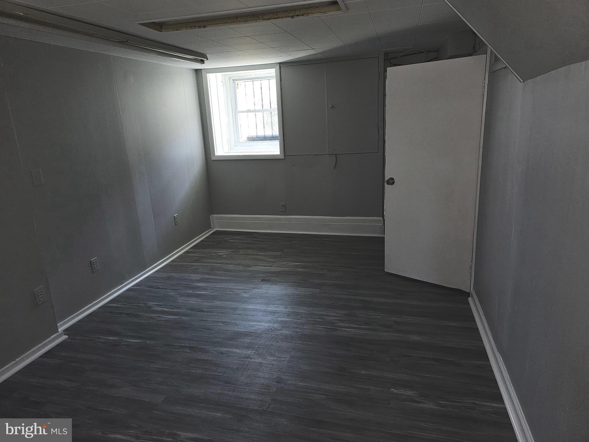 3607 Belair Road, Unit BSMT Baltimore, MD 21213 - Photo 10 of 14 an empty room with wooden floor and windows