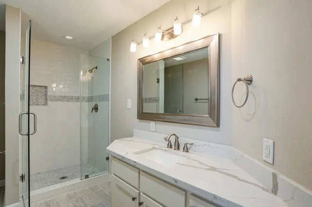 a bathroom with a granite countertop sink mirror and shower