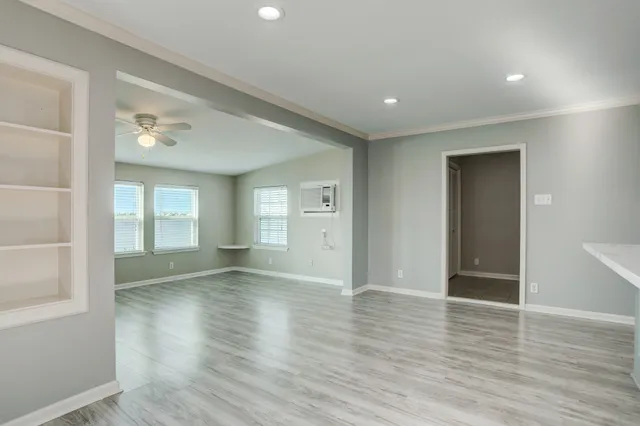 an empty room with wooden floor and windows