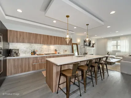 a kitchen with stainless steel appliances kitchen island granite countertop a table chairs sink and cabinets