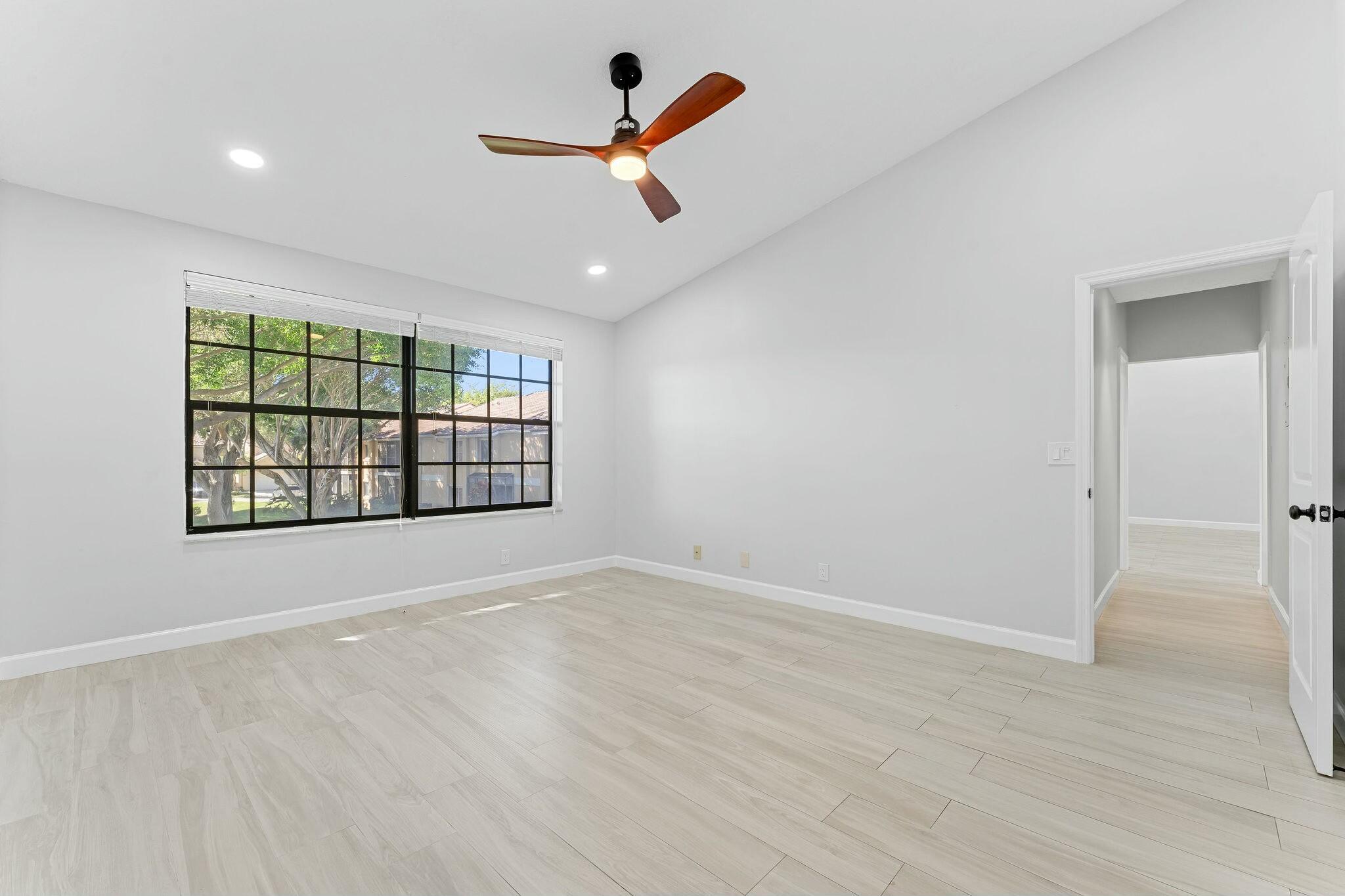 23032 Island View, Unit H Boca Raton, FL 33433 - Photo 11 of 30 an empty room with ceiling fan and windows