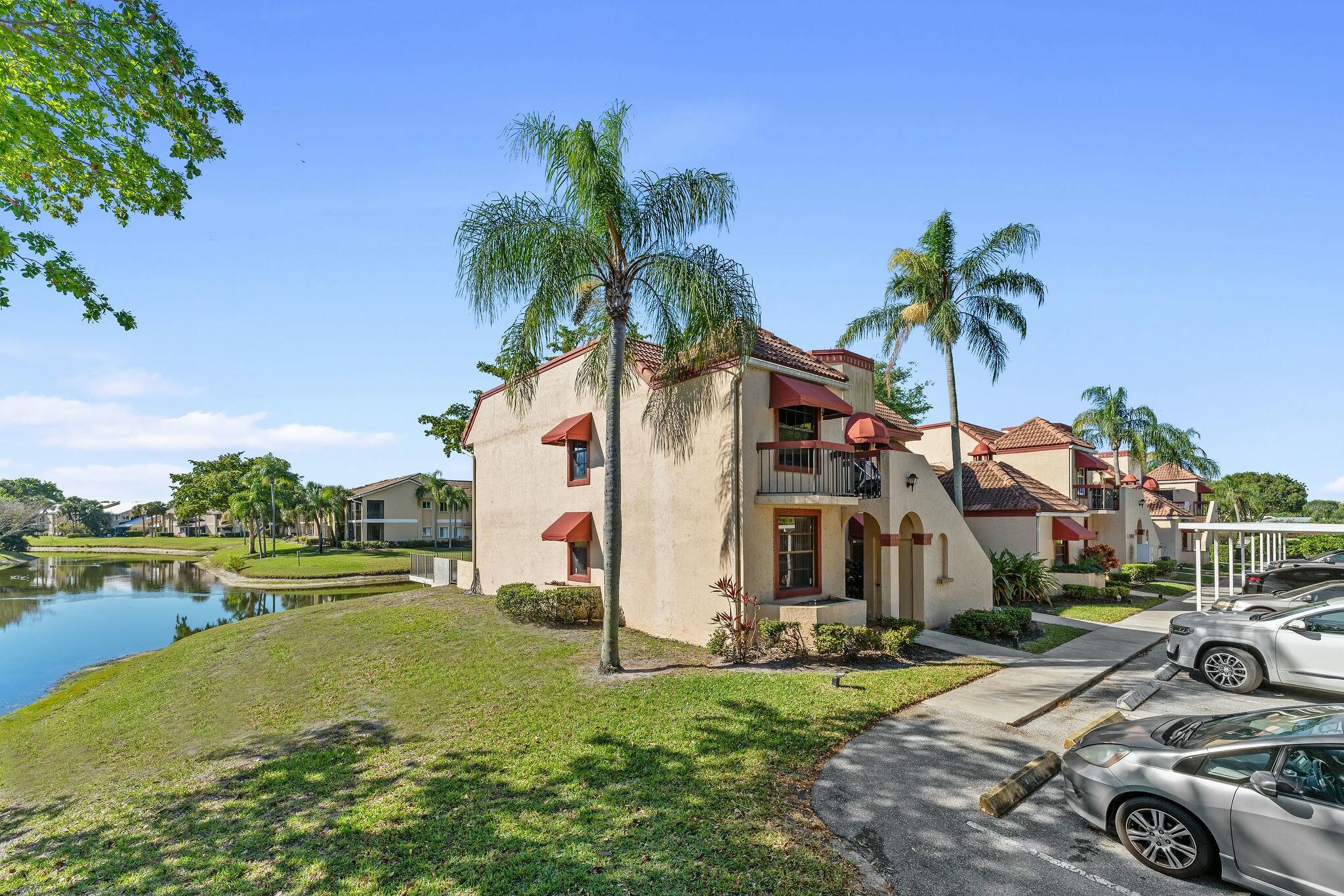 23032 Island View, Unit H Boca Raton, FL 33433 - Photo 29 of 30 a view of a white house with a yard and table and chairs under an umbrella