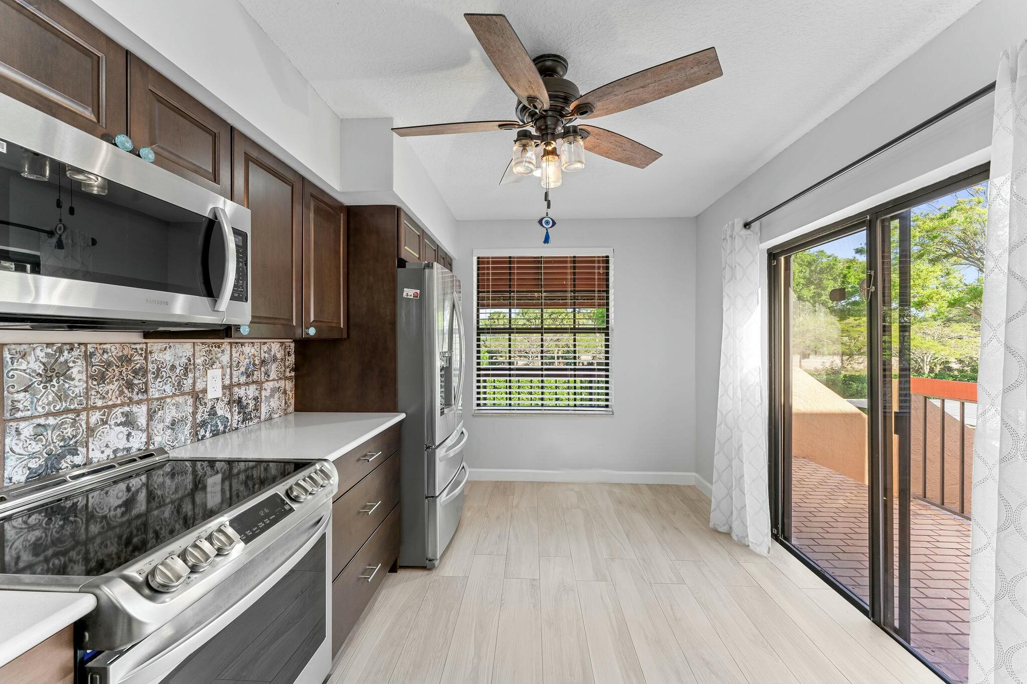 23032 Island View, Unit H Boca Raton, FL 33433 - Photo 8 of 30 a kitchen with a stove a sink and a microwave