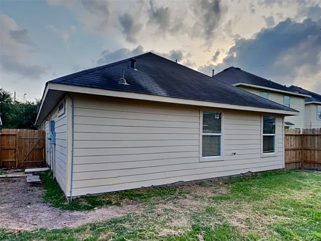 a view of backyard of house with wooden fence
