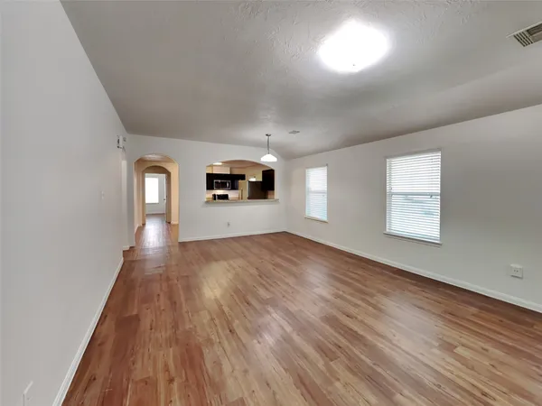 an empty room with wooden floor and windows