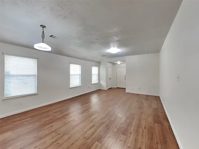 an empty room with wooden floor and windows