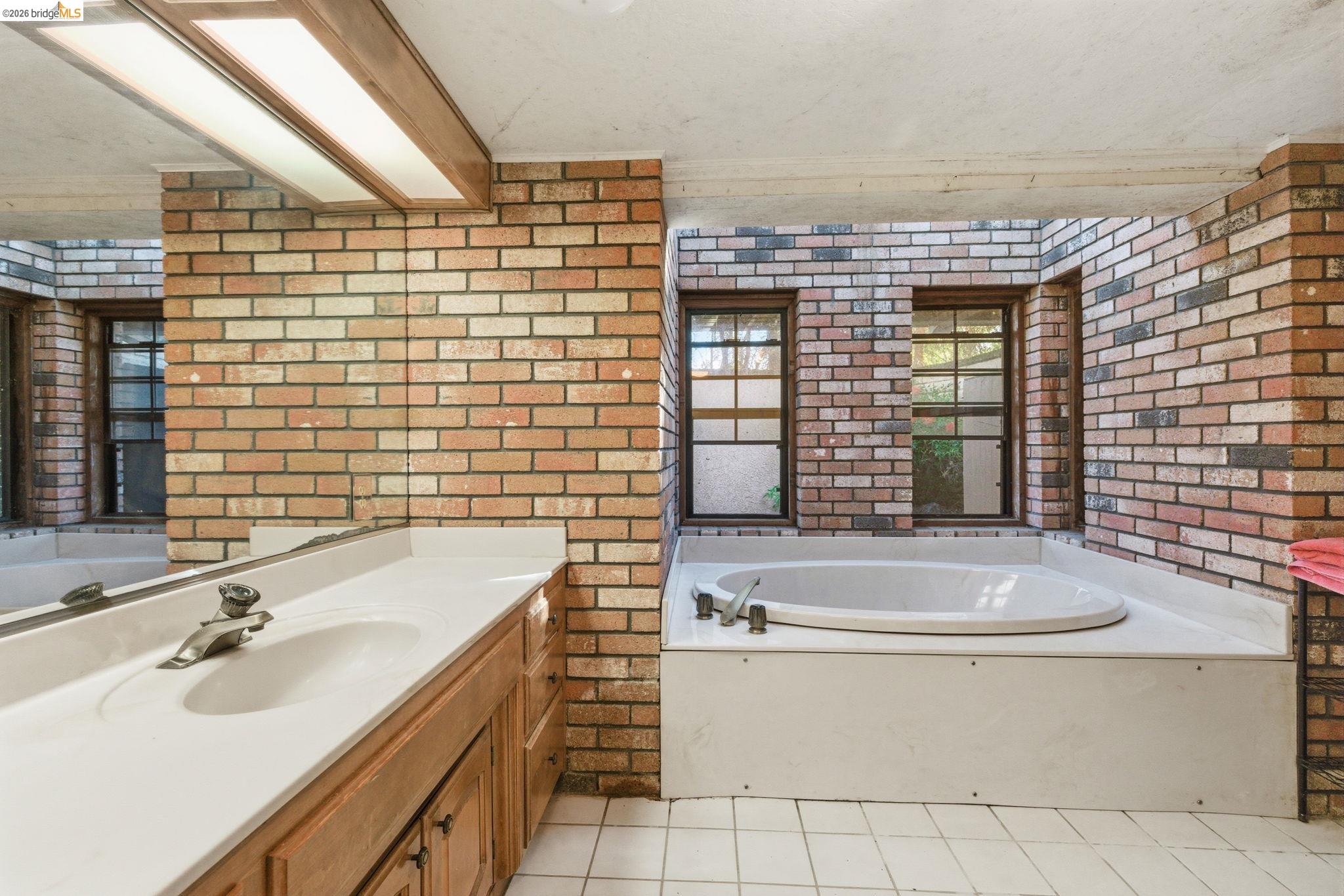 23608 Porcina Way Columbia, CA 95310 - Photo 18 of 51 Bathroom featuring vanity, a bath, brick wall, and light tile patterned floors