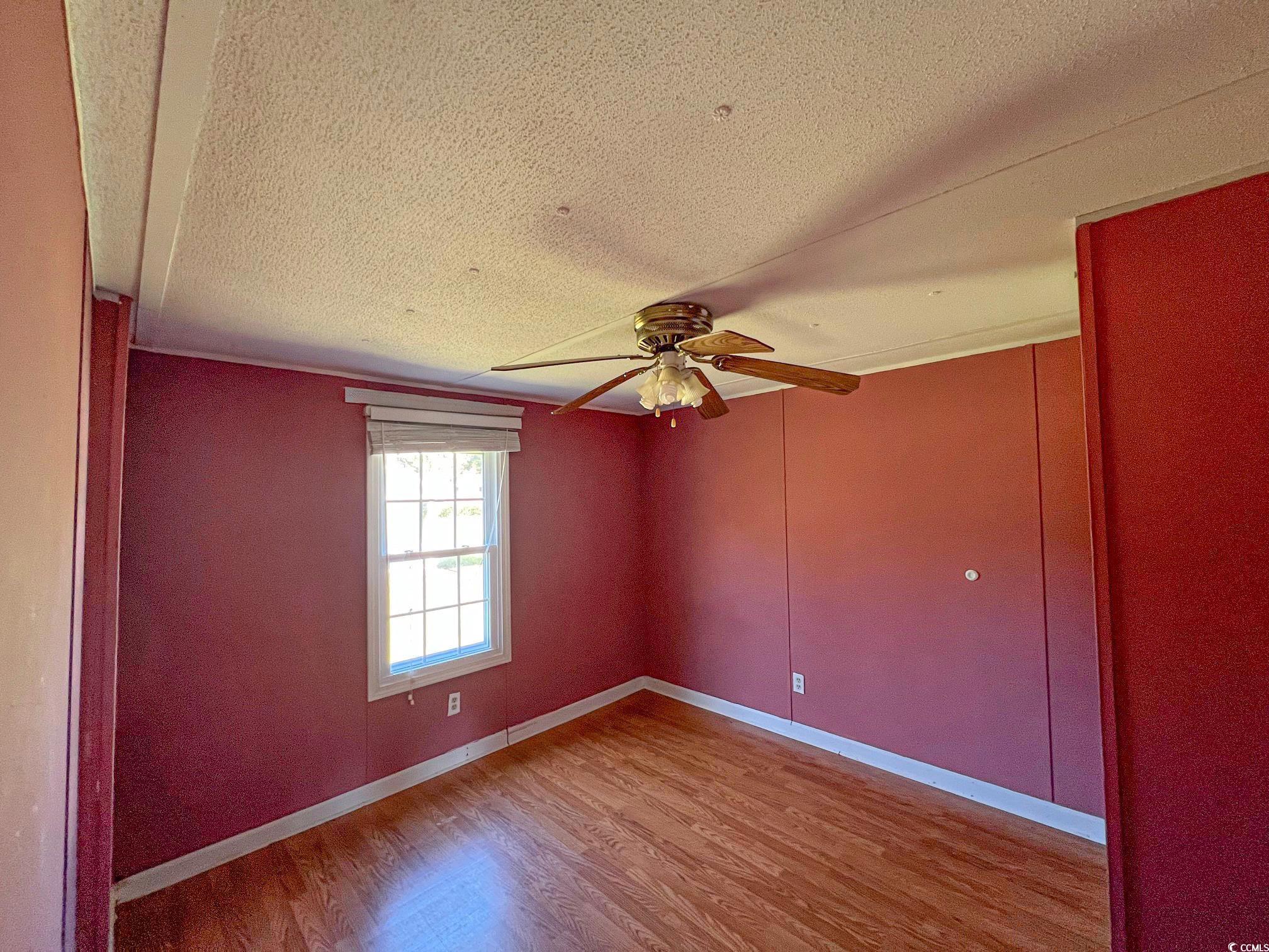 room with hardwood / wood-style flooring, ceiling fan, and a textured ceiling