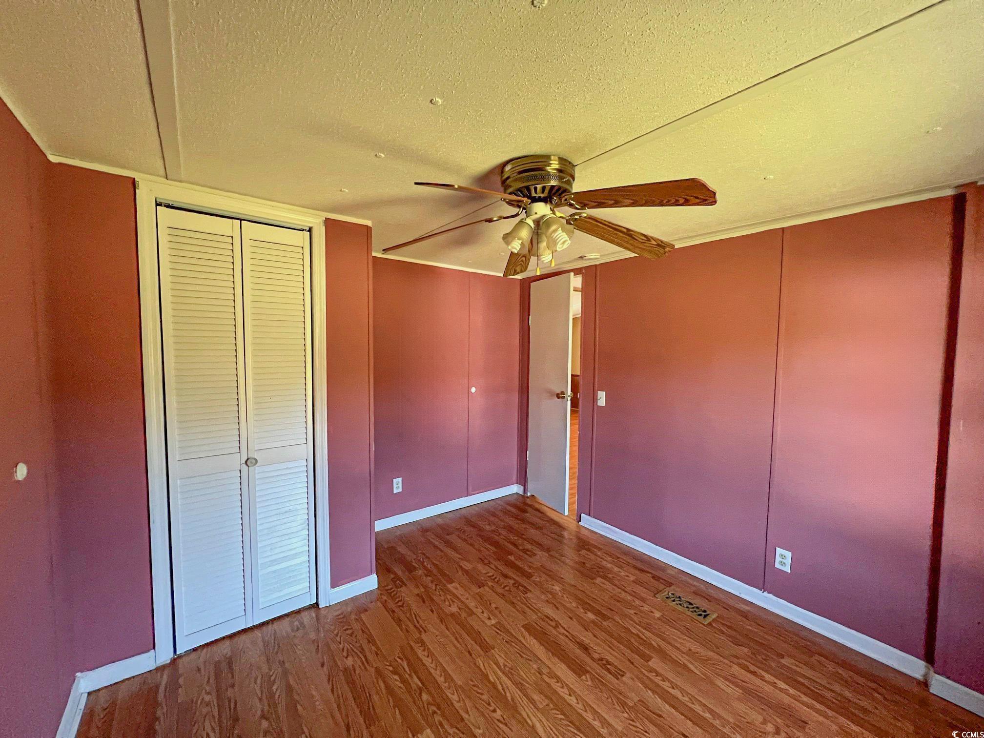 Unfurnished bedroom featuring a textured ceiling, hardwood / wood-style flooring, and ceiling fan