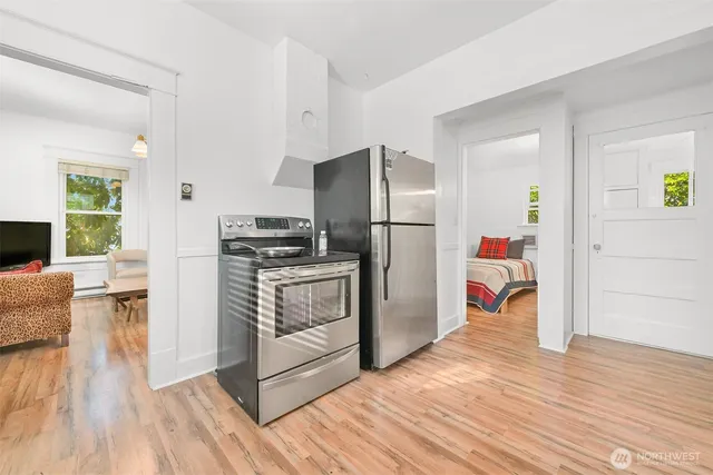 a kitchen with granite countertop a refrigerator a stove a dining table and chairs with wooden floor