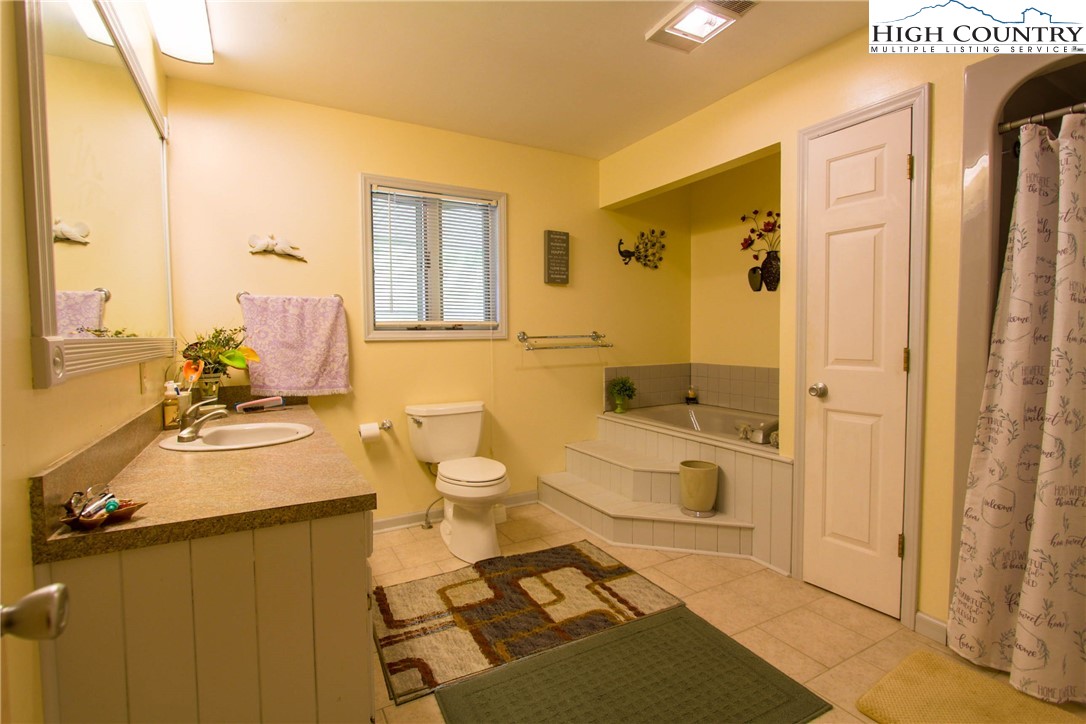 581 North Fork New River Road Lansing, NC 28643 - Photo 28 of 44 a spacious bathroom with a granite countertop sink and a mirror