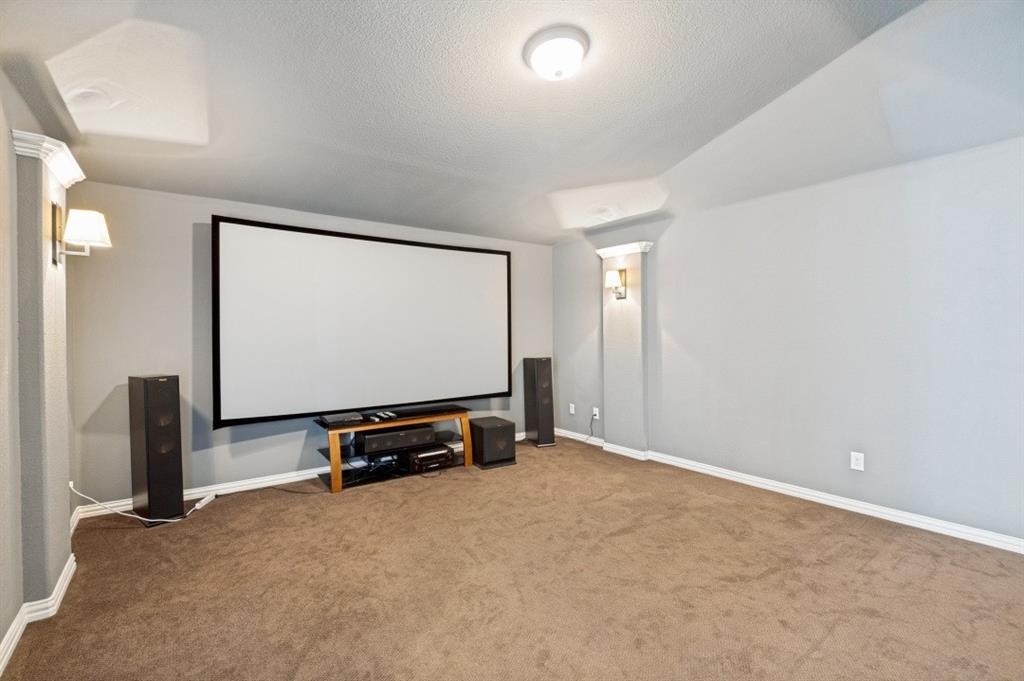 14215 Raspberry Lane Frisco, TX 75035 - Photo 16 of 30 Dedicated media room featuring a large projection screen, wall sconces, and neutral carpeting