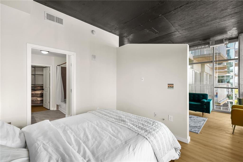250 Pharr Road Northeast, Unit 1702 Atlanta, GA 30305 - Photo 12 of 23 a bedroom with a bed and wooden floor