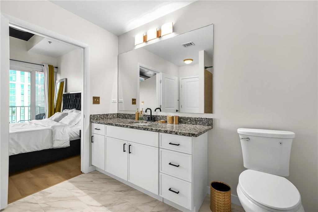 250 Pharr Road Northeast, Unit 1702 Atlanta, GA 30305 - Photo 21 of 23 a bathroom with a granite countertop toilet sink and mirror