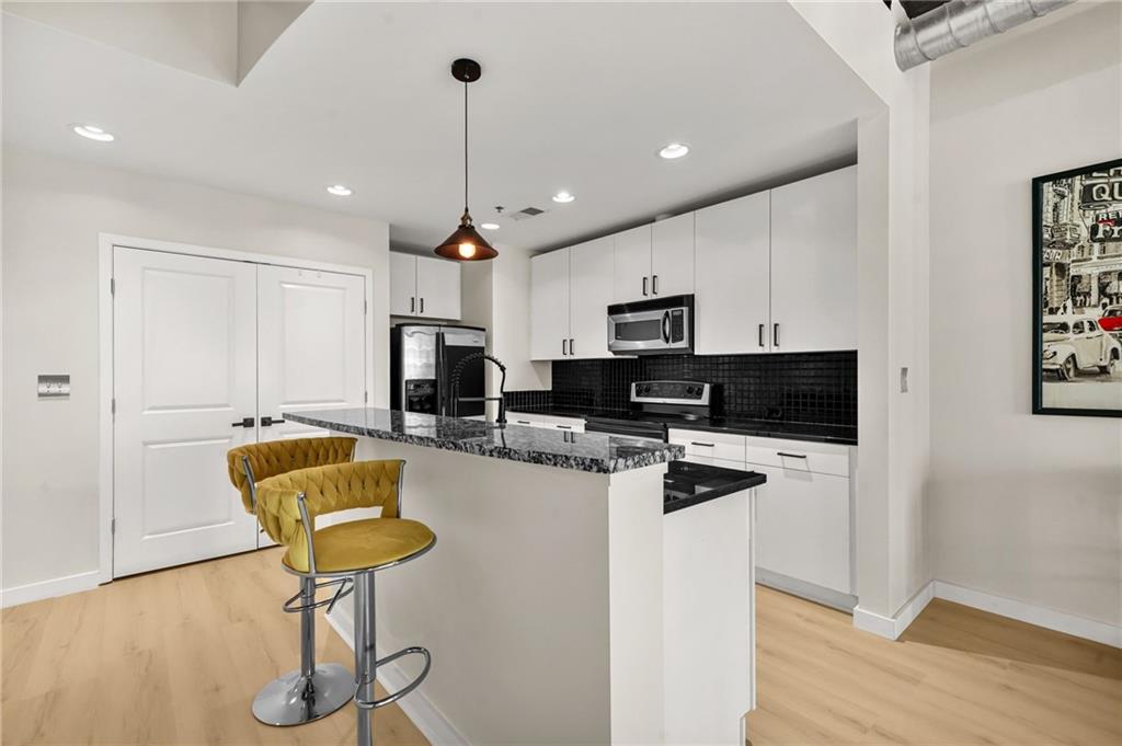 250 Pharr Road Northeast, Unit 1702 Atlanta, GA 30305 - Photo 6 of 23 a kitchen with stainless steel appliances kitchen island granite countertop a refrigerator a stove a microwave oven a sink with island and chairs with wooden floor